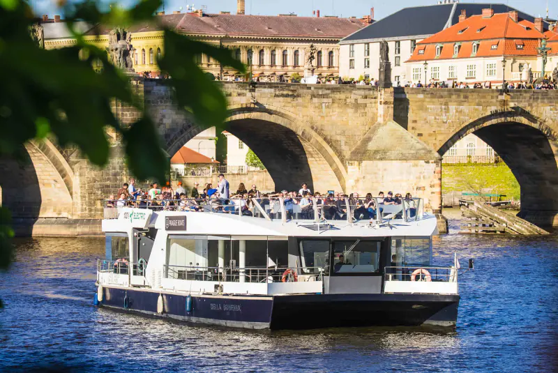 An electric sightseeing boat beside Charles Bridge